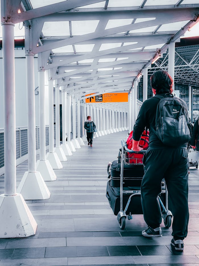 Travelers with luggage trolleys navigating through Dortmund Airport's terminal walkway.