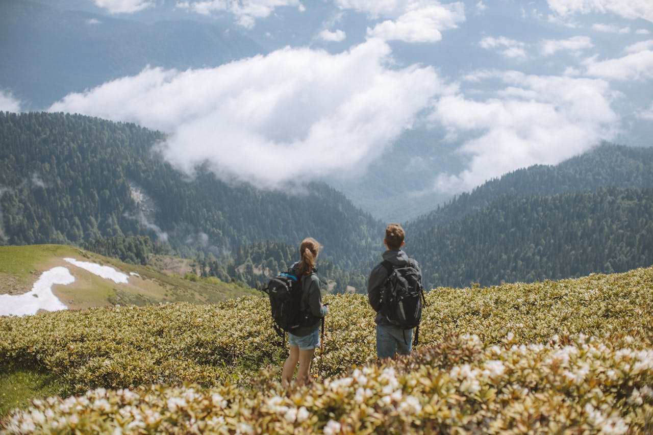 Two hikers with backpacks admire a stunning mountain landscape. Perfect for travel and adventure themes.